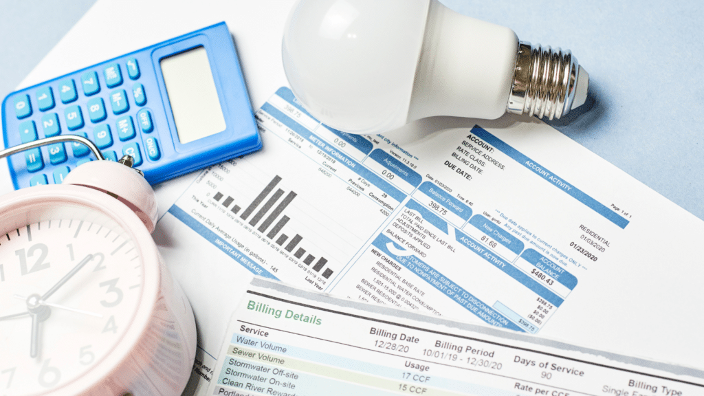 An energy bill showing usage details and cost, surrounded by a light bulb, a blue calculator, and part of a clock. The image suggests the concept of managing or calculating energy consumption and expenses.