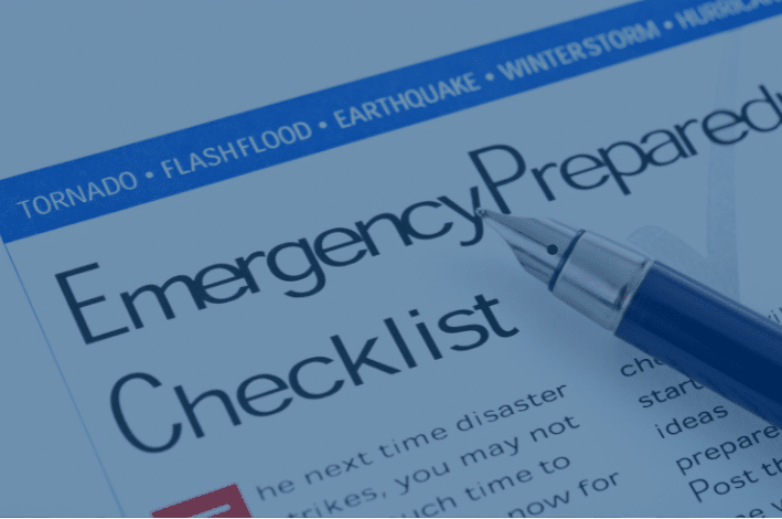 Close-up of a paper titled Emergency Preparedness Checklist underlined in blue. A pen rests on the paper. Headings above include Tornado, Flash Flood, Earthquake, Winter Storm, and Hurricane against a blue background.